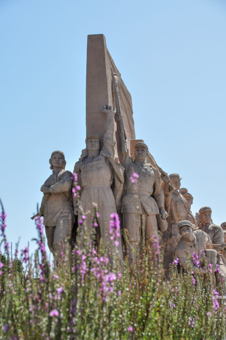 Low-angle view of the revolutionary-era figural relief group at the Monument to the People’s Heroes, showing idealized workers, soldiers, and civilians carved in pale stone.