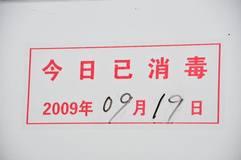 Close-up of a red-bordered Chinese sanitation notice reading “disinfected today,” dated 2009-09-19 at Beijing Airport.
