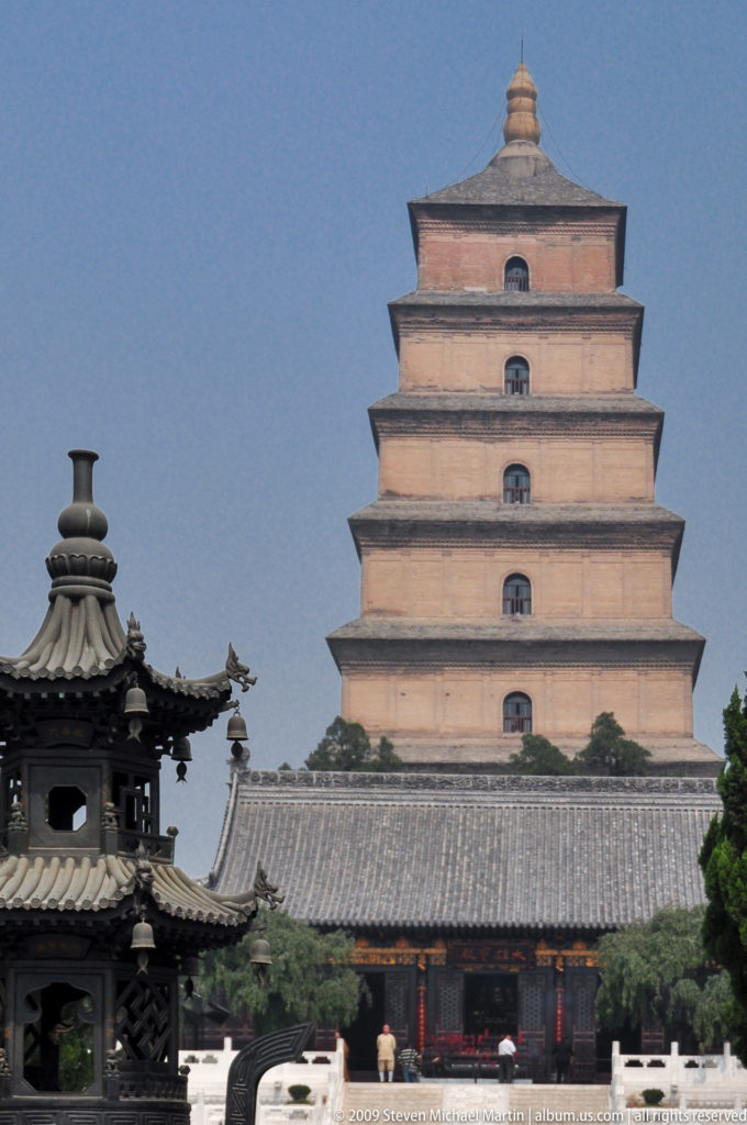 Telephoto view of the lower and middle tiers of the Giant Wild Goose Pagoda rising behind a small dark pavilion with upturned eaves.