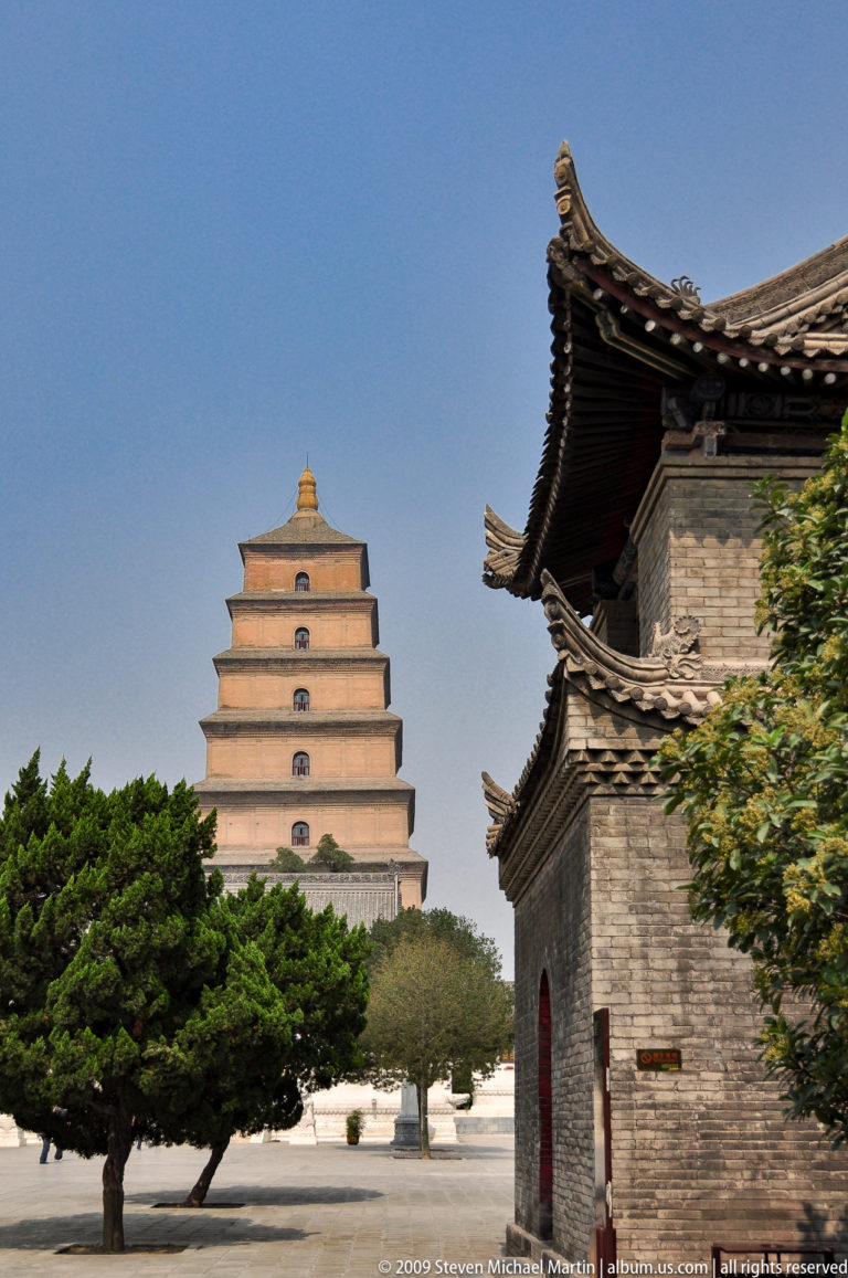 Giant Wild Goose Pagoda seen beyond traditional gray-tiled temple roofs and trees within the Da Ci'en Temple complex.