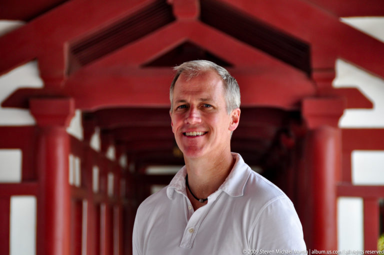 Male visitor standing in a red-painted covered corridor with repeating timber columns at Da Ci'en Temple in Xi'an.
