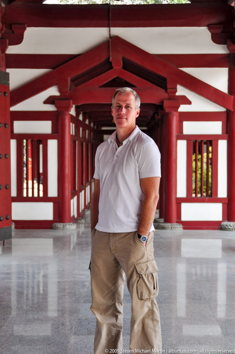 Male visitor standing in a red-painted temple corridor with repeating columns at Da Ci'en Temple in Xi'an.