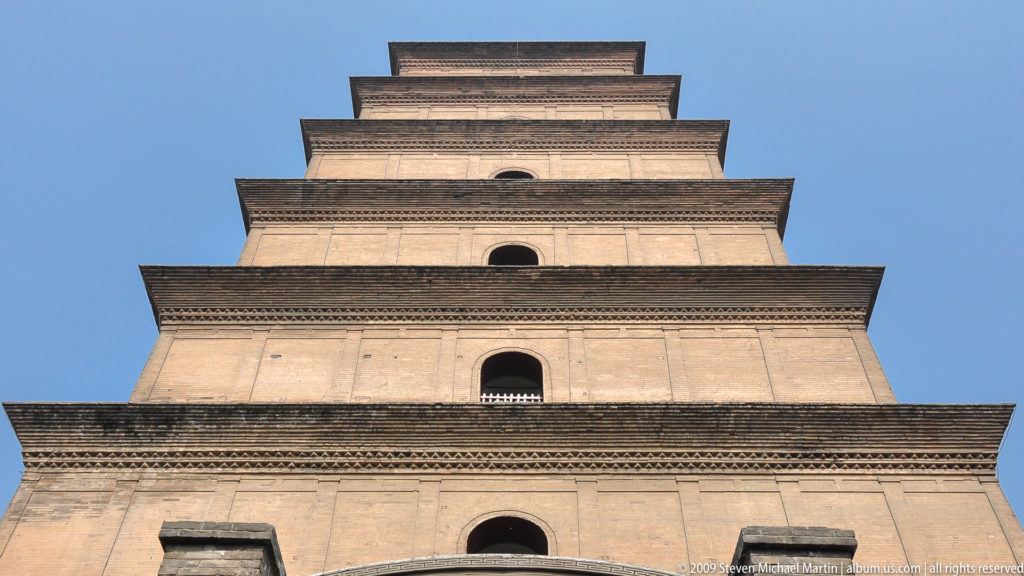 Low-angle frontal view of the Giant Wild Goose Pagoda’s seven-tiered brick facade, with dark arched openings and horizontal cornice bands narrowing toward the top.