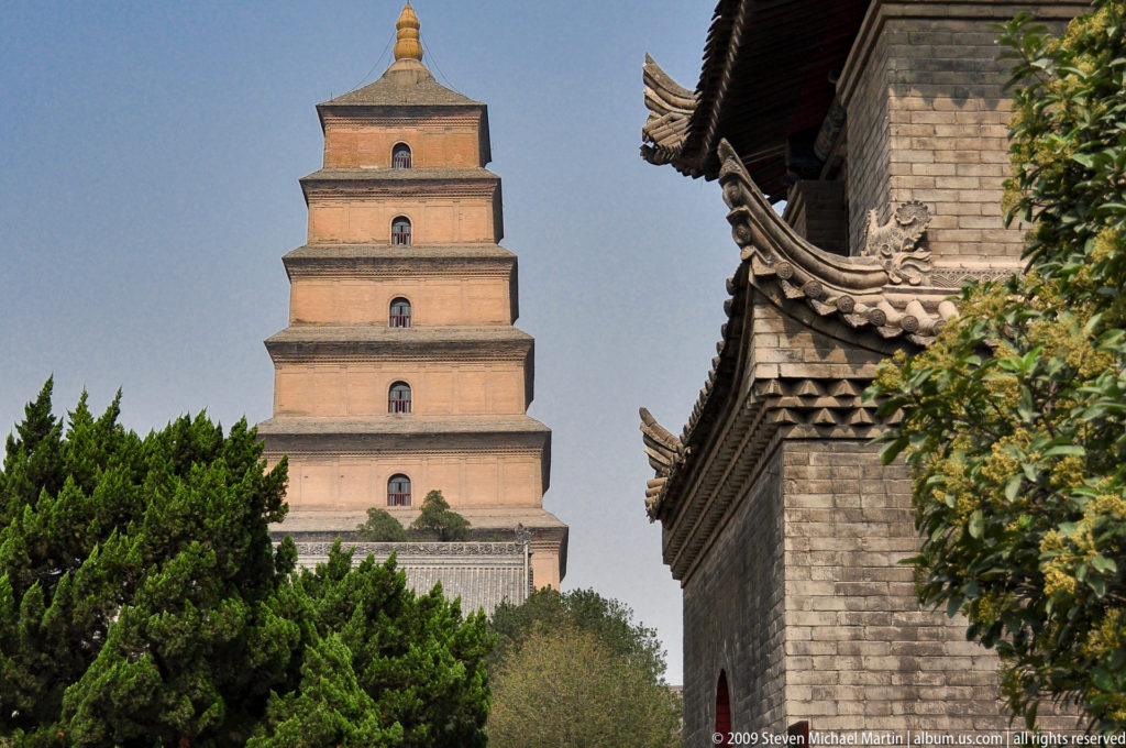 Giant Wild Goose Pagoda seen beyond gray-brick temple roofs and trees within the Da Ci'en Temple complex in Xi'an.