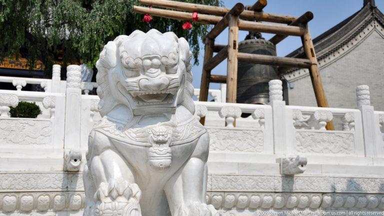 White stone guardian lion sculpture in front of the bell at Da Ci'en Temple in Xi'an.