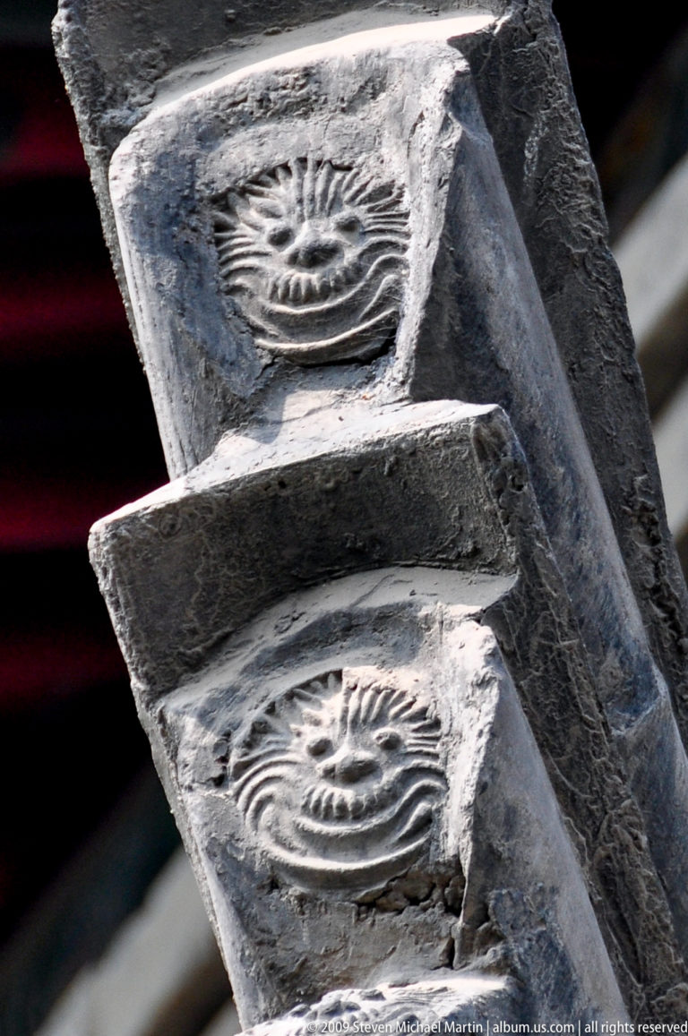 Close-up of weathered gray ceramic roof elements with stepped layers and a circular radiating motif.
