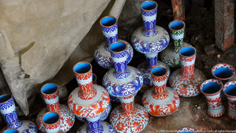 Cluster of brightly painted long-necked ceramic souvenir vases with dense floral and scroll patterns.