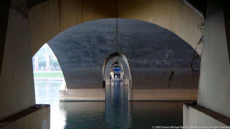 Repeating concrete bridge arches over water forming a tunnel-like view in Guilin, China.