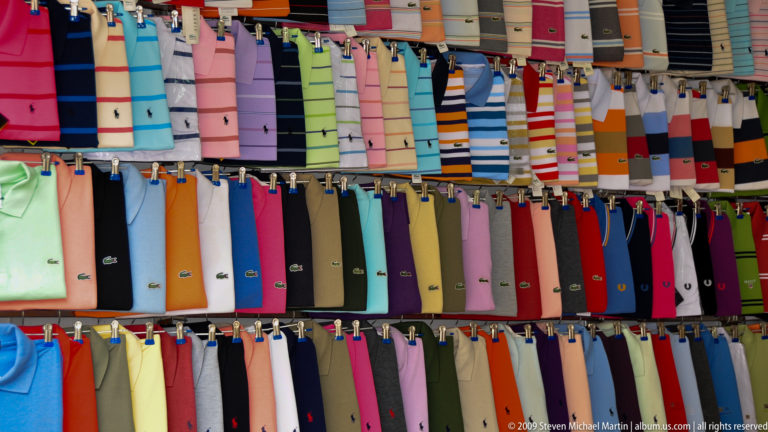 Rows of colorful patterned neckties clipped side by side on a Yangshuo market wall.