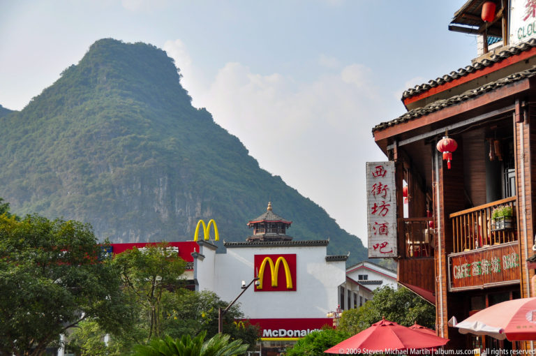 McDonald’s storefront in Yangshuo with traditional-style buildings and red lanterns, set below a steep green karst hill.