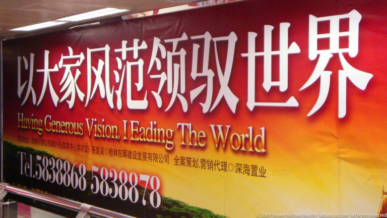 Red-orange Chinese real-estate billboard in Guilin with large Chinese characters, the English slogan “Generous Vision, Leading The World,” and phone numbers 5838868 and 5838878.