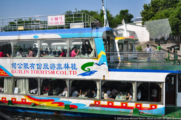 Two-deck Guilin Tourism Co. sightseeing boat crowded with passengers cruising on the Li River.