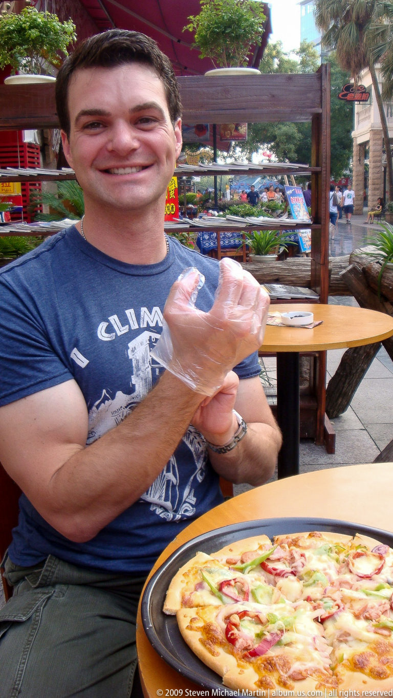 Close-up of a traveler in Guilin adjusting a transparent disposable food-service glove over his wrist.