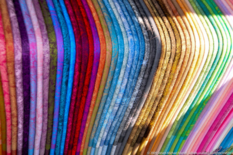 Rows of brightly colored folded merchandise in parallel stripes at a Guilin market stall.