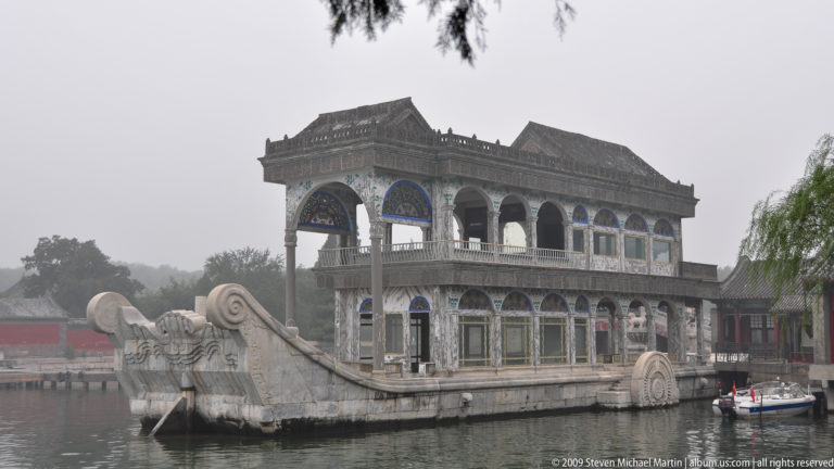 Oblique view of the Marble Boat with stone hull, two-story pavilion, arched windows, and decorative wheel forms on Kunming Lake.