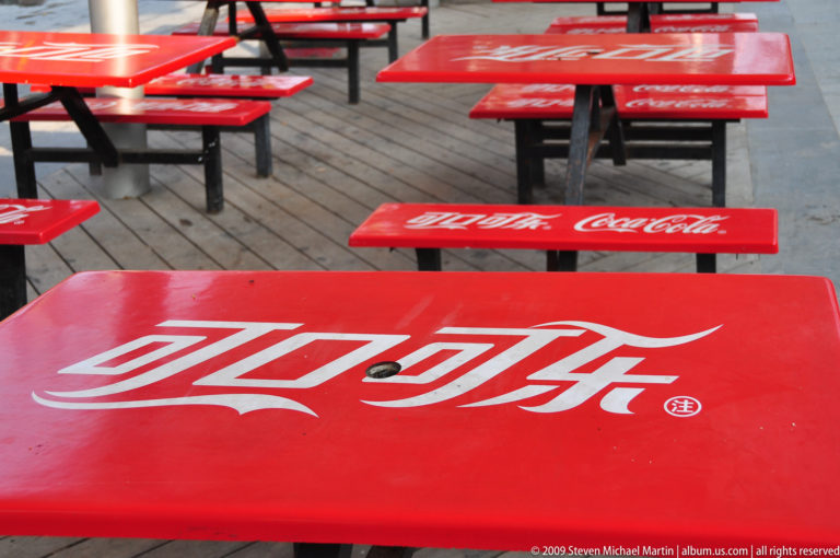Rows of bright red outdoor café tables with Chinese and English Coca-Cola logos at the Terracotta Army museum complex near Xi’an.