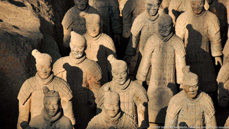 Overhead view of a tightly packed group of life-sized armored terracotta soldiers with individualized faces and topknots.