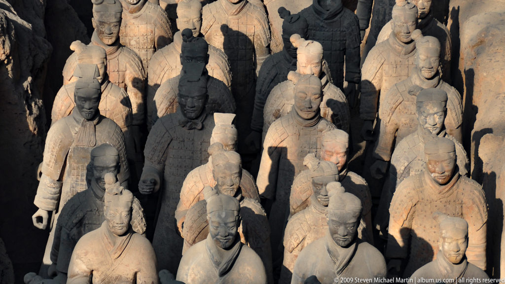 High-angle view of densely packed Qin dynasty terracotta infantry figures with varied hairstyles and armor at the Terracotta Army museum complex near Xi'an.
