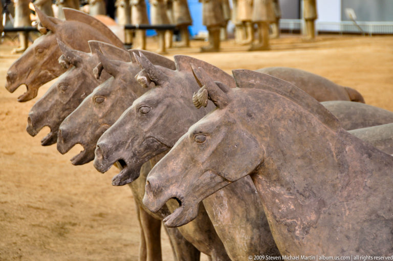 Diagonal row of terracotta horse heads from the Qin dynasty Terracotta Army, mouths open and ears upright.