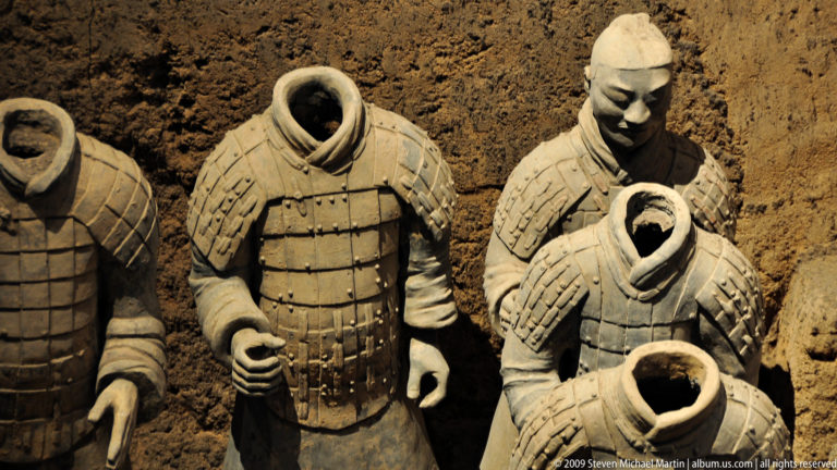 Headless standing terracotta warrior figures with hollow neck openings and intact armor plates at the Terracotta Army museum complex near Xi’an.