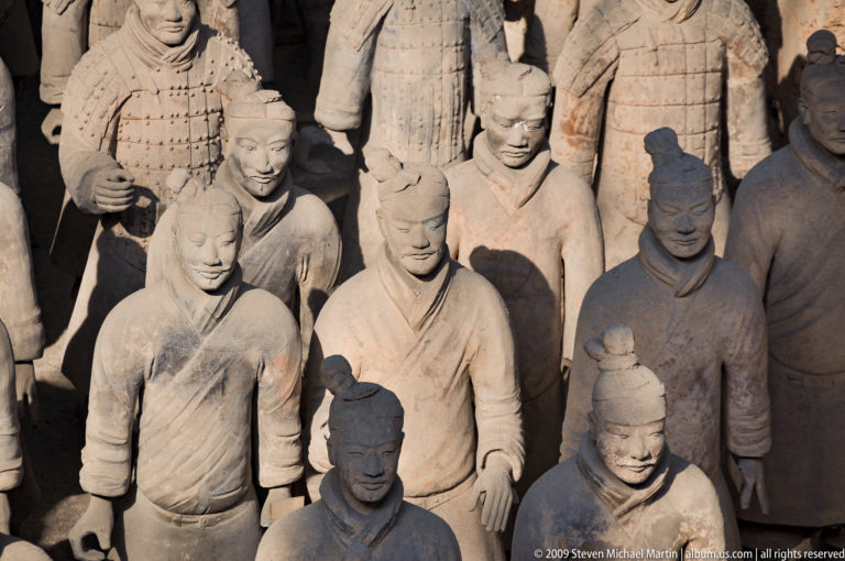 Group of unarmored terracotta soldiers in robed uniforms standing in formation at the Terracotta Army site.