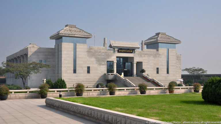 Symmetrical modern exhibition building at the Terracotta Army archaeological site near Xi'an, viewed from across a formal lawn.