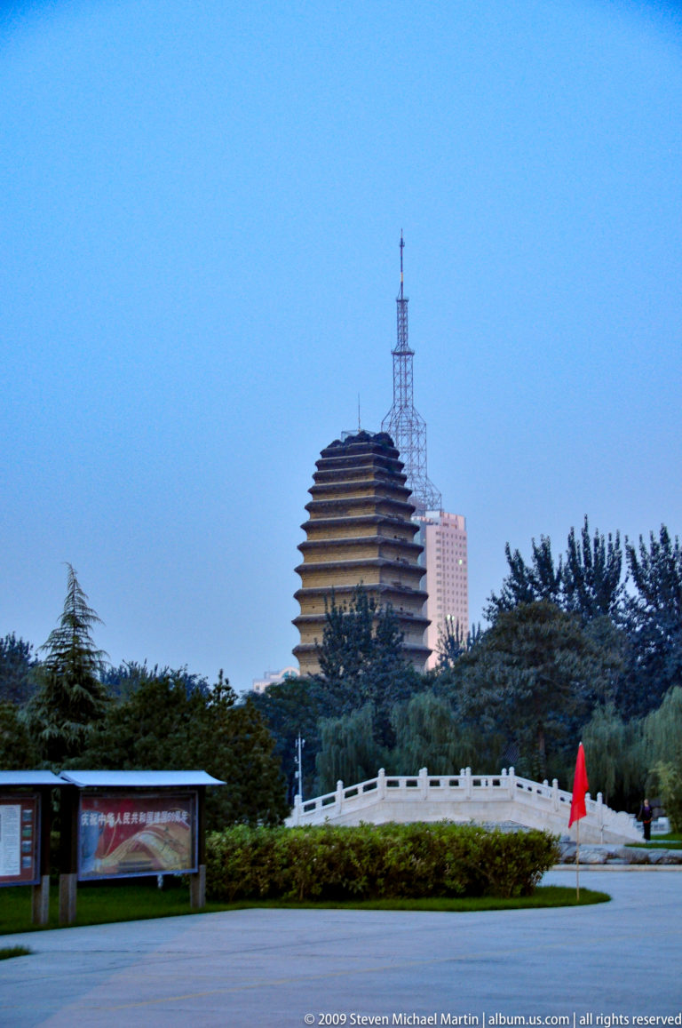 Small Wild Goose Pagoda, a Tang-dynasty brick Buddhist tower, rising above trees in a Xi’an park with modern high-rise buildings behind.