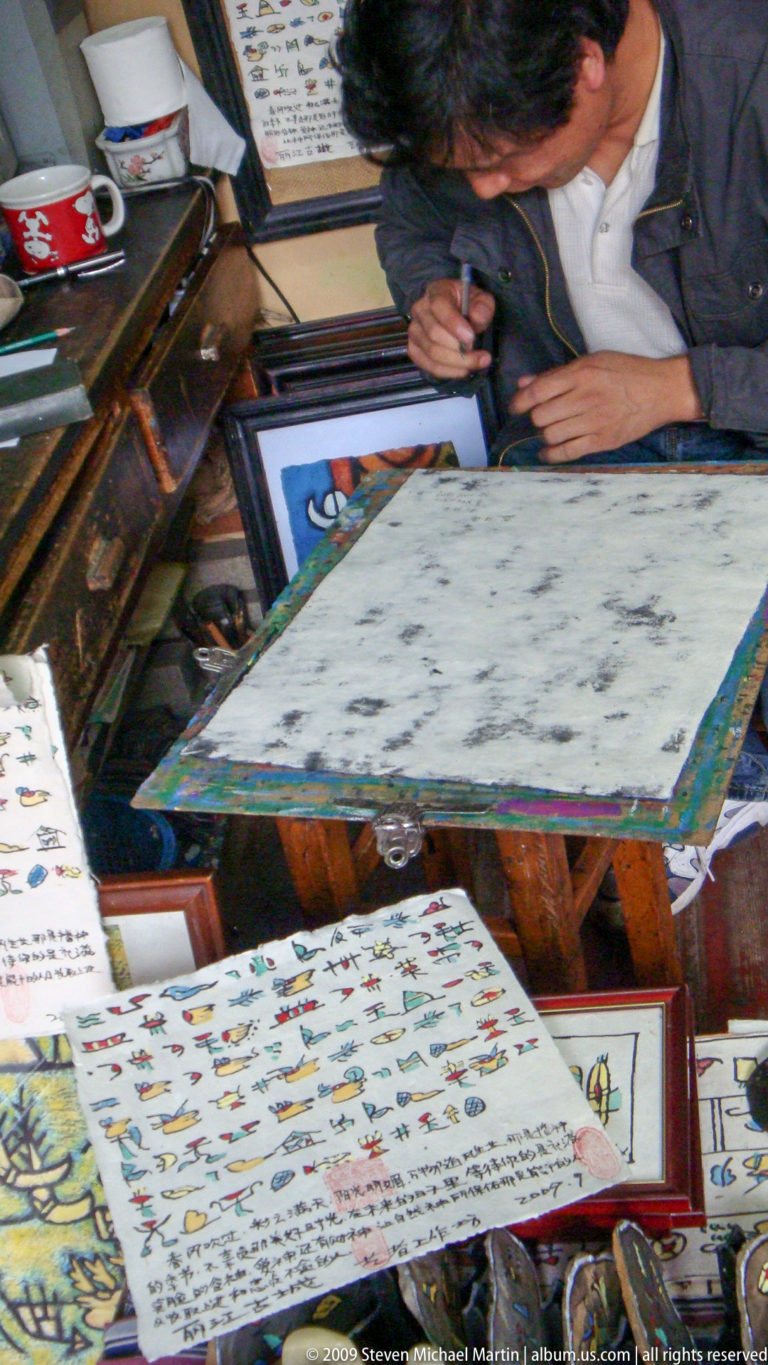 Ink-stained flat board or printing plate on a wooden worktable, with scattered dark impressions and surrounding printed sheets and tools.