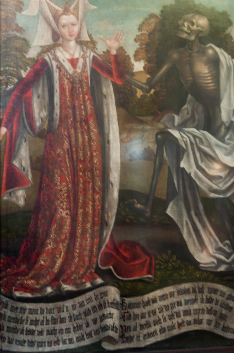 Richly dressed woman in red beside a draped skeleton in the Dance of Death, with Low German verse painted along the bottom.