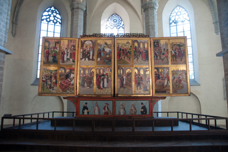 Wide sanctuary view of the half-open Hermen Rode high-altar retable beneath tall pointed windows in St Nicholas Church.
