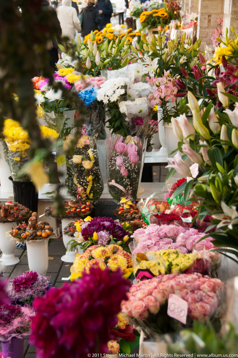 Dense Tallinn flower-market display with colorful bouquets and cut flowers arranged in buckets and on tables.