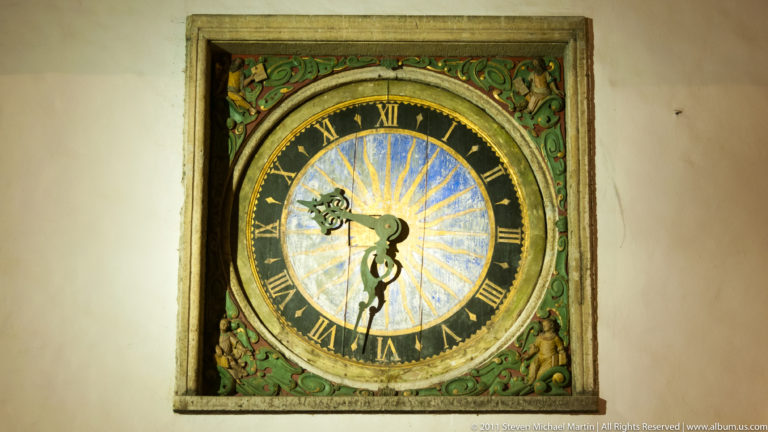 Close-up of the Church of the Holy Spirit’s painted clock with Roman numerals and carved ornament.