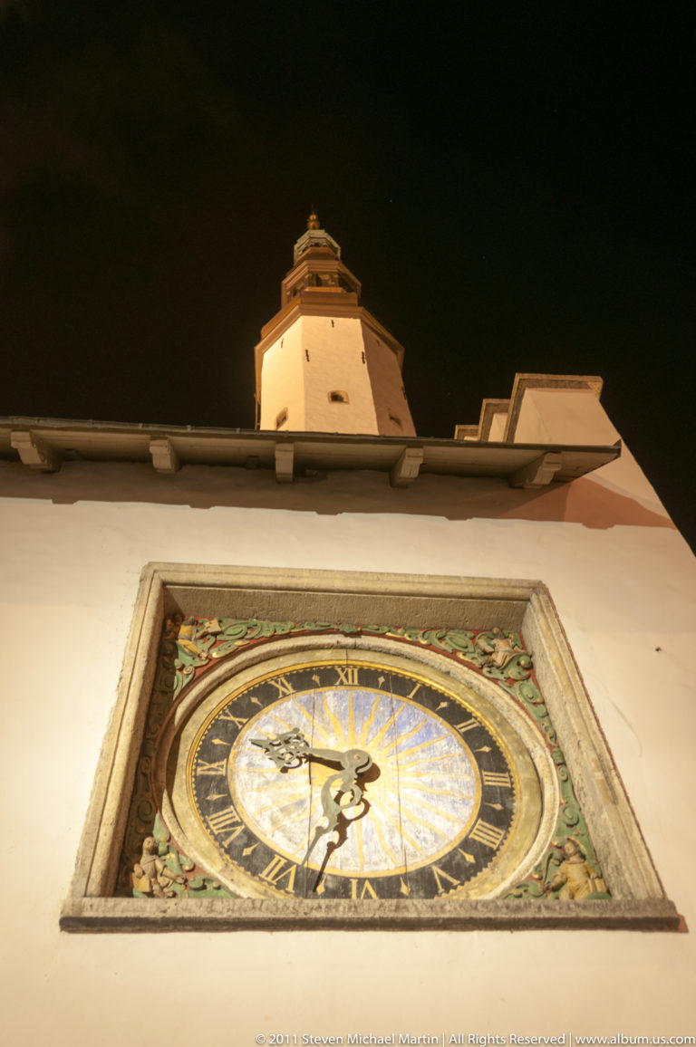 Painted exterior clock of the Church of the Holy Spirit on an illuminated wall at night.