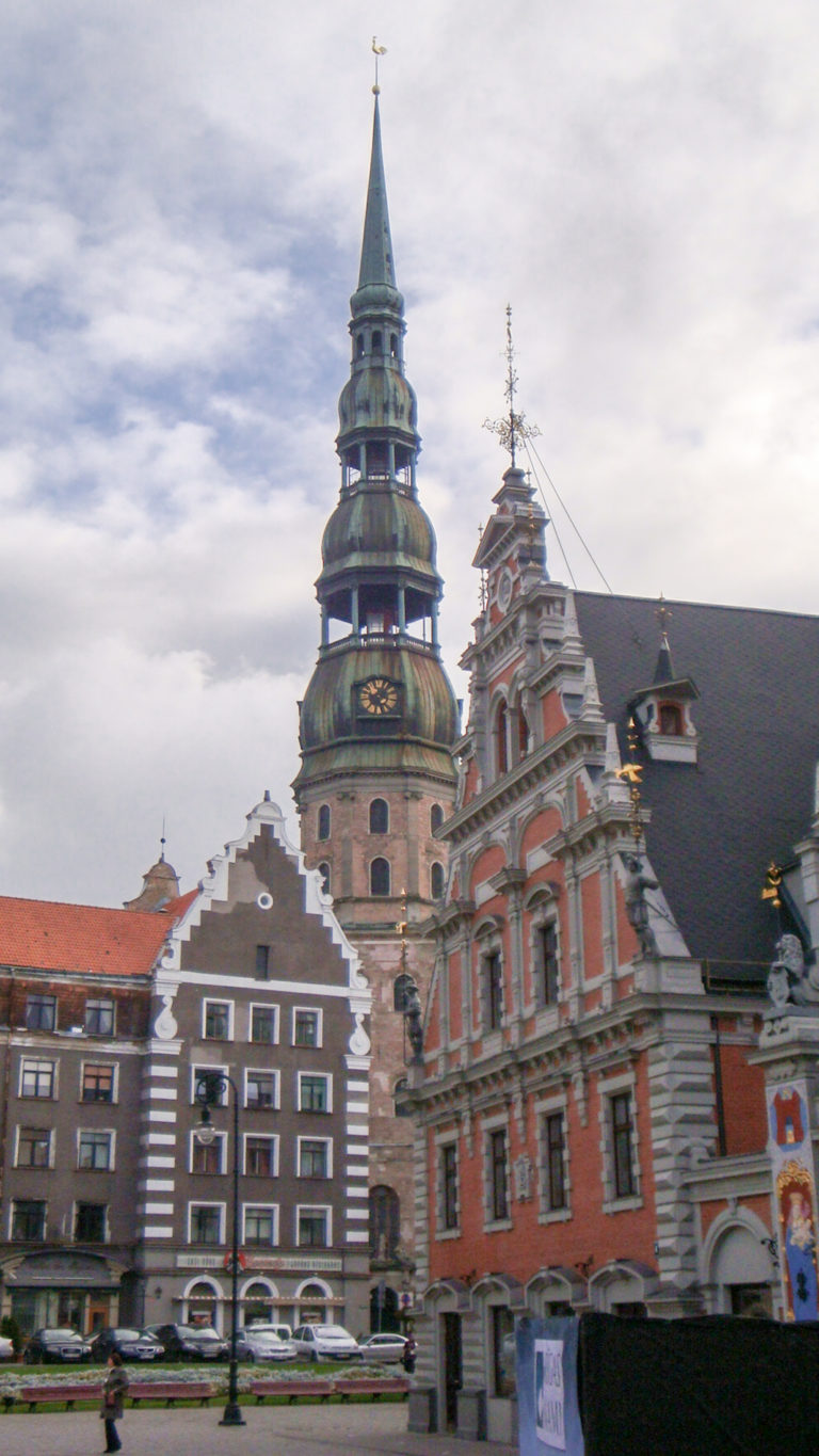 St. Peter’s Church tower rising behind gray and red historic gabled buildings in Old Riga.