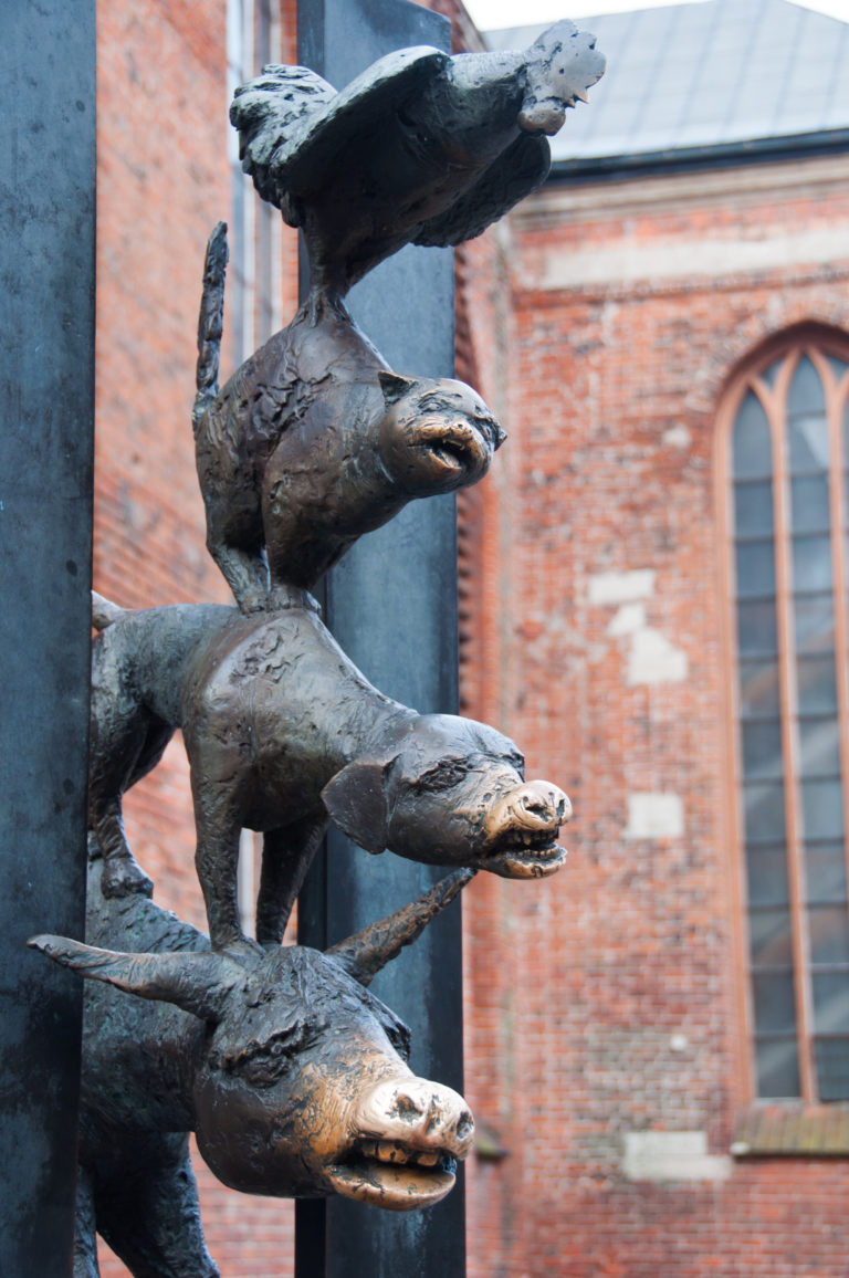 Close side view of stacked bronze donkey, dog, cat, and rooster heads on the Bremen Town Musicians sculpture.