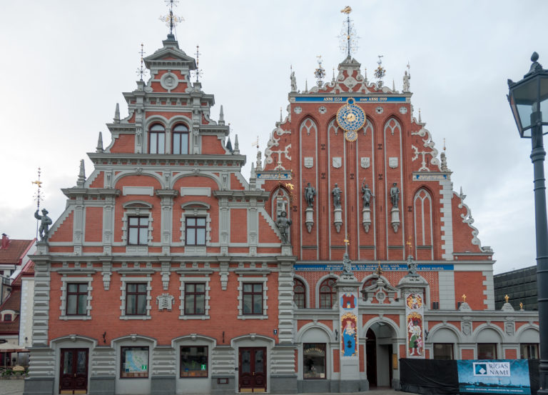 Full red-brick House of the Blackheads façade with stepped gables, statues, coats of arms, clock, and gilded ornaments.
