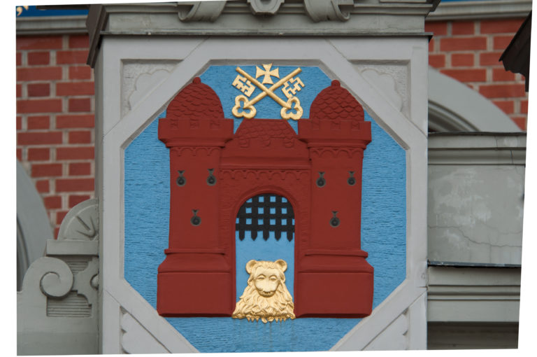 Heraldic shield with red fortified gate, crossed gold keys, and golden lion head on a blue field.