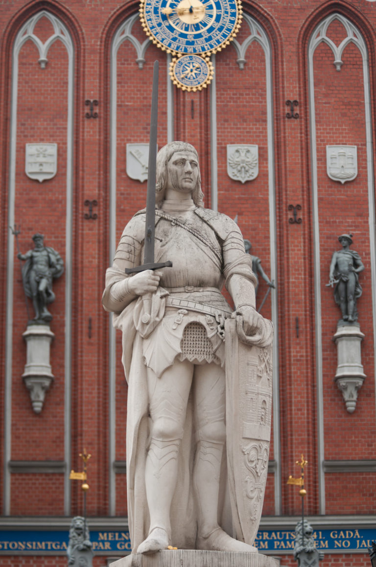 Armored Roland statue holding sword and shield before the red-brick House of the Blackheads.