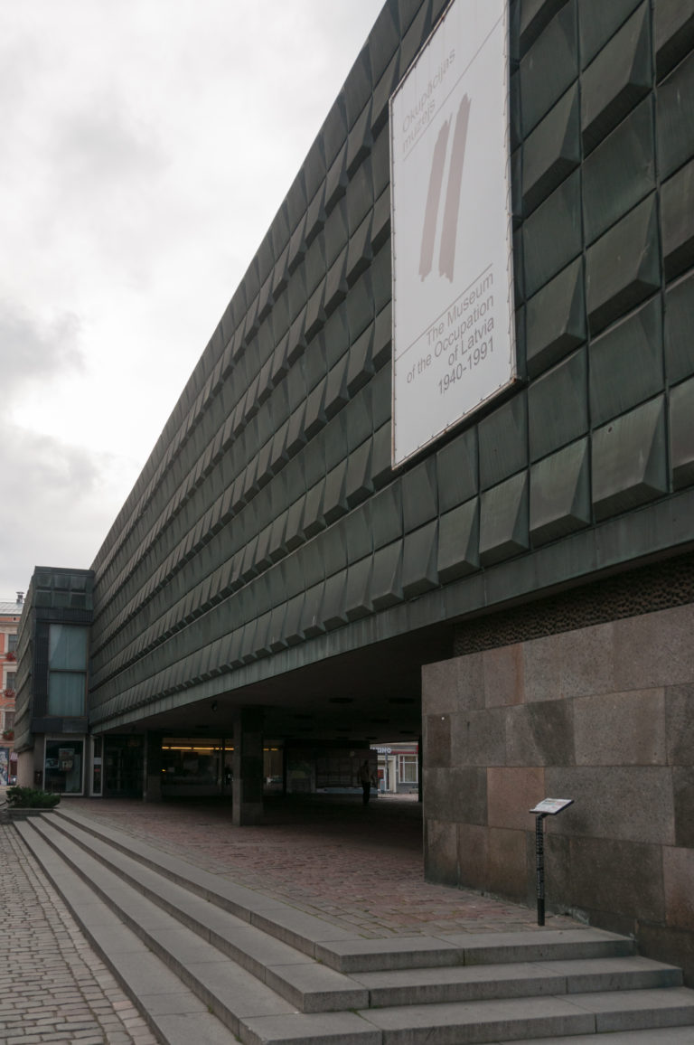 Dark modernist exterior of the Museum of the Occupation of Latvia with a large 1940–1991 sign.