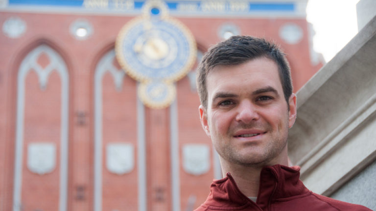 Close portrait of a man with the House of the Blackheads and its clock blurred behind him.