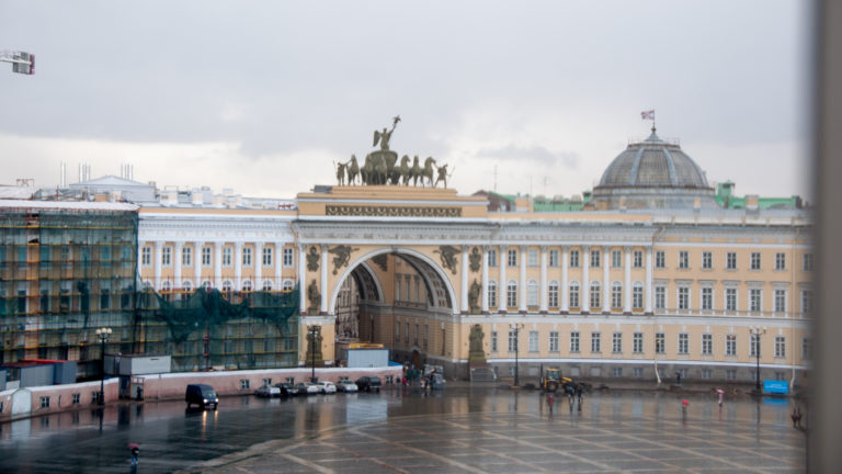 General Staff Building arch and curved façade across wet Palace Square under a gray sky.