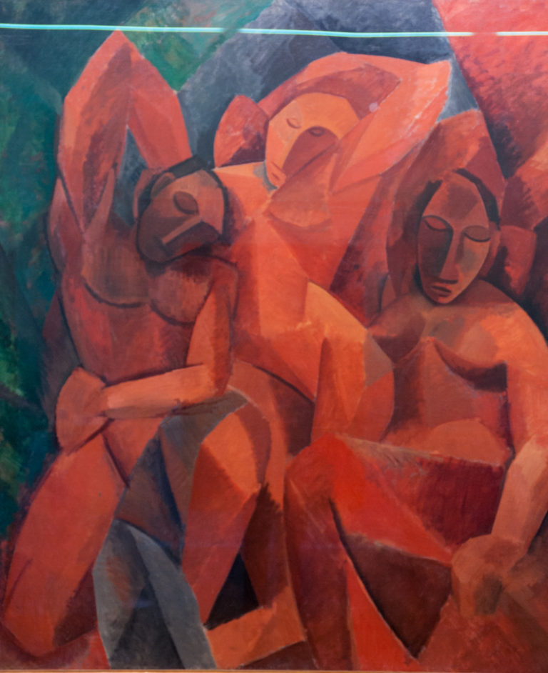 Pablo Picasso’s Three Women, with three interlocked female figures constructed from angular red, rust, ocher, green, and gray forms.