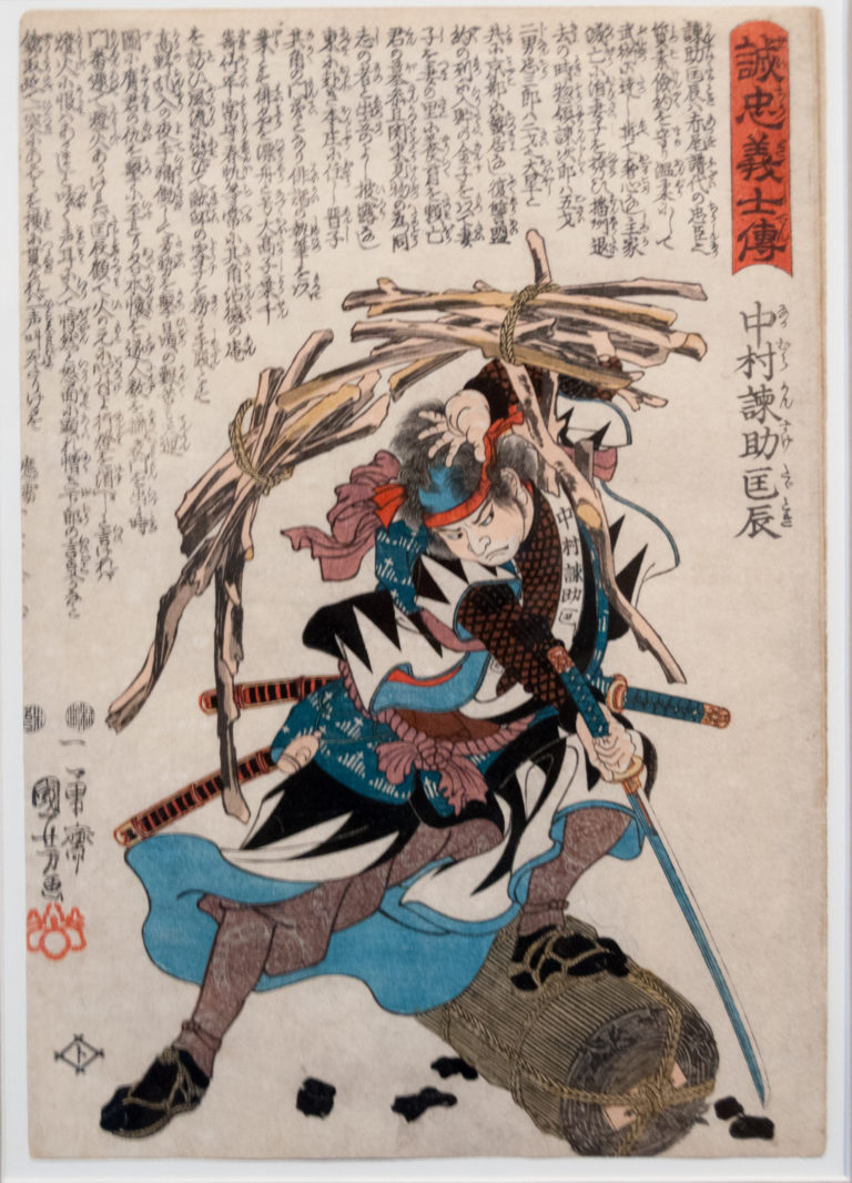 Kuniyoshi woodblock print of Nakamura Kansuke Tadatoki crouching with drawn sword beneath falling firewood beside a charcoal bale.