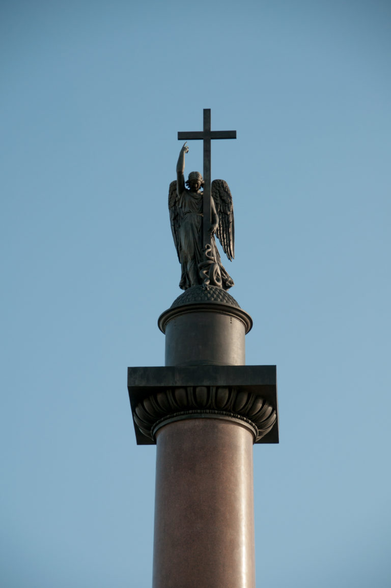 Angel holding a tall cross atop the Alexander Column, seen from below against a clear blue sky.