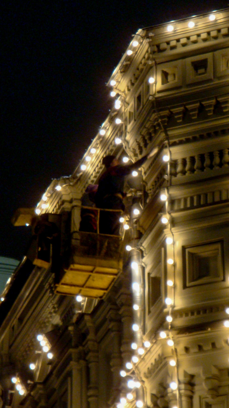Oblique nighttime close-up of an ornate building façade outlined by rows of warm decorative lights.