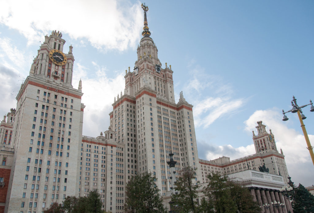 Low oblique view of Moscow State University, with a clock tower at left and the taller central spire behind.