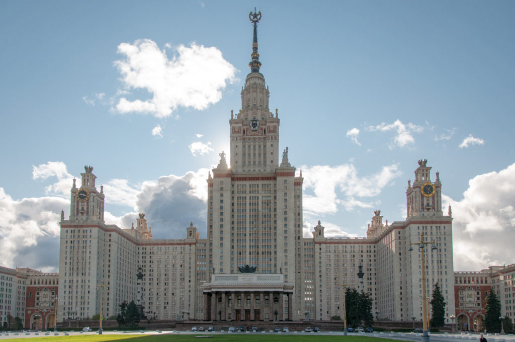 Frontal view of Moscow State University's tall central tower and spire flanked by symmetrical wings and clock towers.