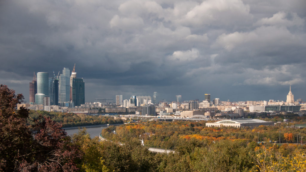 Moscow City glass towers at left above autumn parkland, with central Moscow extending across the distant horizon.