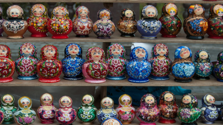 Three shelves packed with elaborately painted matryoshka nesting dolls in red, blue, green, purple, and gold.