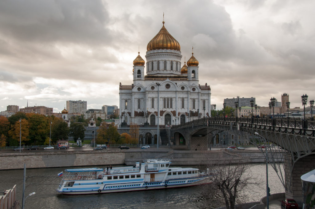 Cathedral of Christ the Saviour beyond the Moscow River with a sightseeing boat and curving pedestrian bridge.